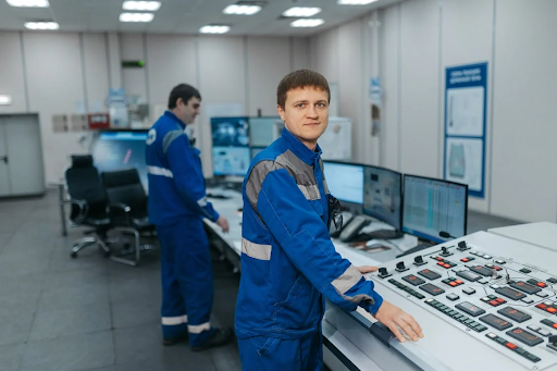 Technicians operating machinery in a control room as part of a safe and ergonomic workplace environment
